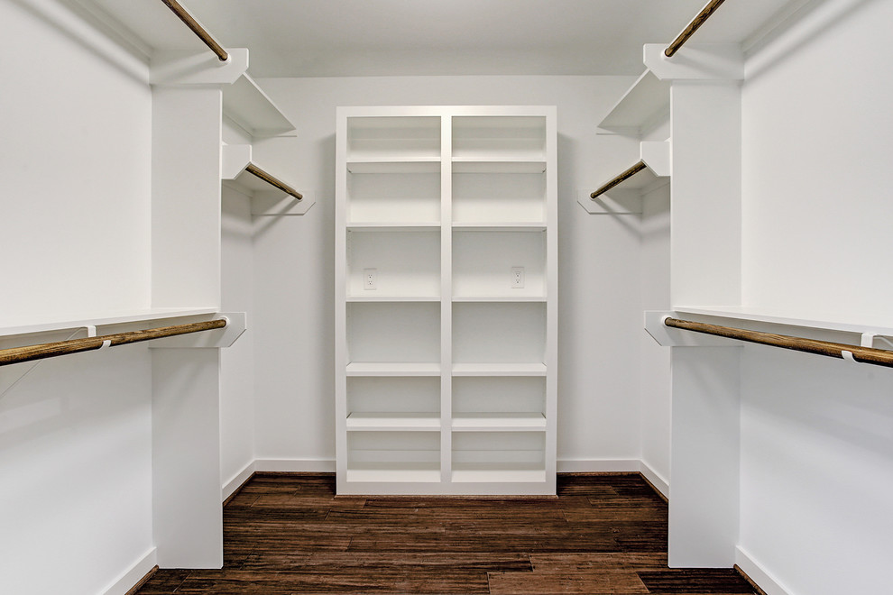 This is an example of a midcentury gender-neutral walk-in wardrobe in Houston with open cabinets, white cabinets, bamboo floors and brown floor.