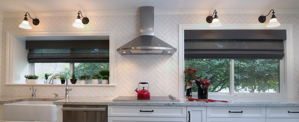 Example of a transitional u-shaped multicolored floor enclosed kitchen design with a farmhouse sink, recessed-panel cabinets, white cabinets, granite countertops, white backsplash, subway tile backsplash, stainless steel appliances, an island and beige countertops