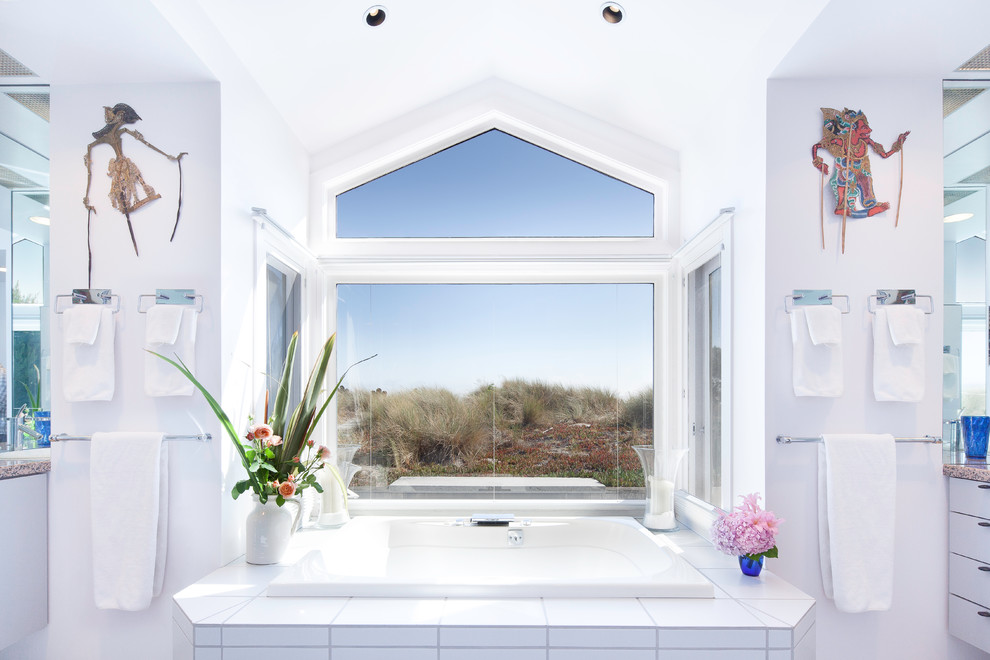 Design ideas for a mid-sized beach style master bathroom in San Francisco with flat-panel cabinets, white cabinets, granite benchtops, a drop-in tub, white tile, porcelain tile and white walls.