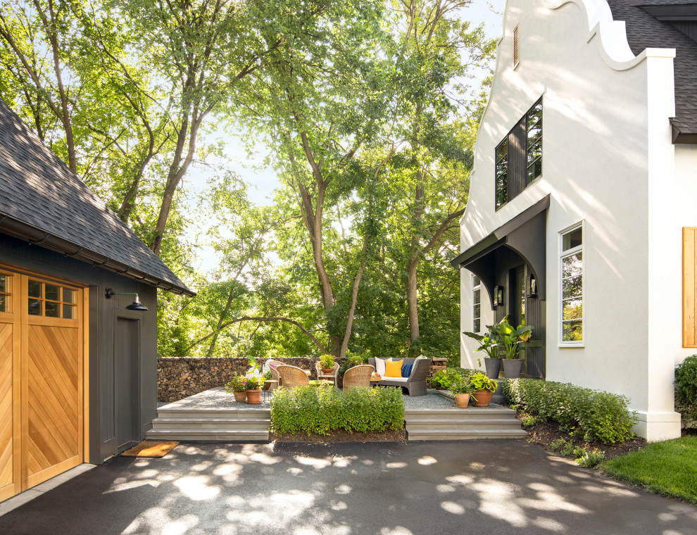 Small eclectic two-storey stucco white house exterior in Minneapolis with a gable roof and a shingle roof.
