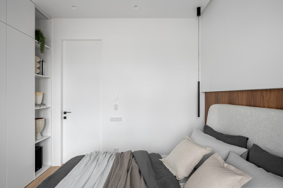 Imagen de dormitorio principal y gris y blanco actual de tamaño medio sin chimenea con paredes blancas, suelo de madera clara, suelo beige y panelado