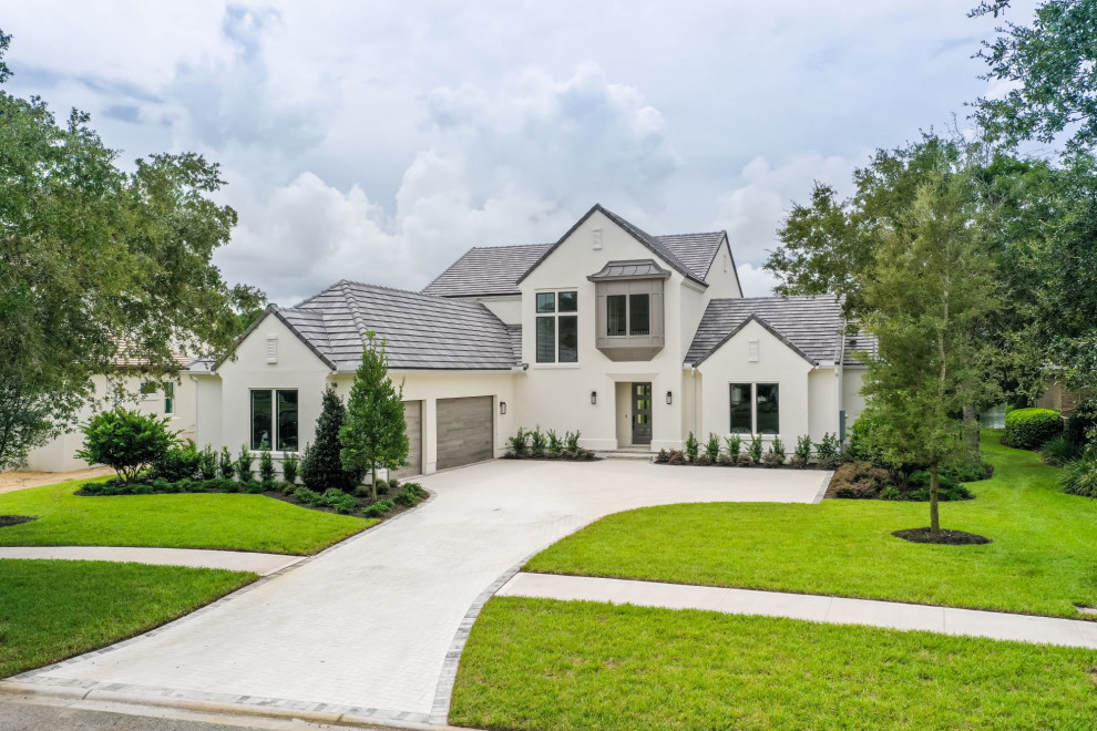 Photo of a large transitional two-storey stucco white house exterior in Jacksonville with a gable roof, a tile roof, a grey roof and board and batten siding.