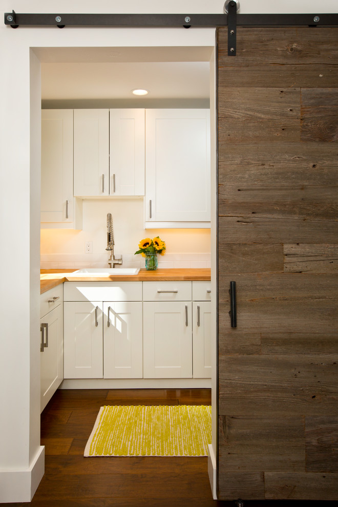 This is an example of a transitional single-wall utility room in Other with a single-bowl sink, wood benchtops, white walls and dark hardwood floors.