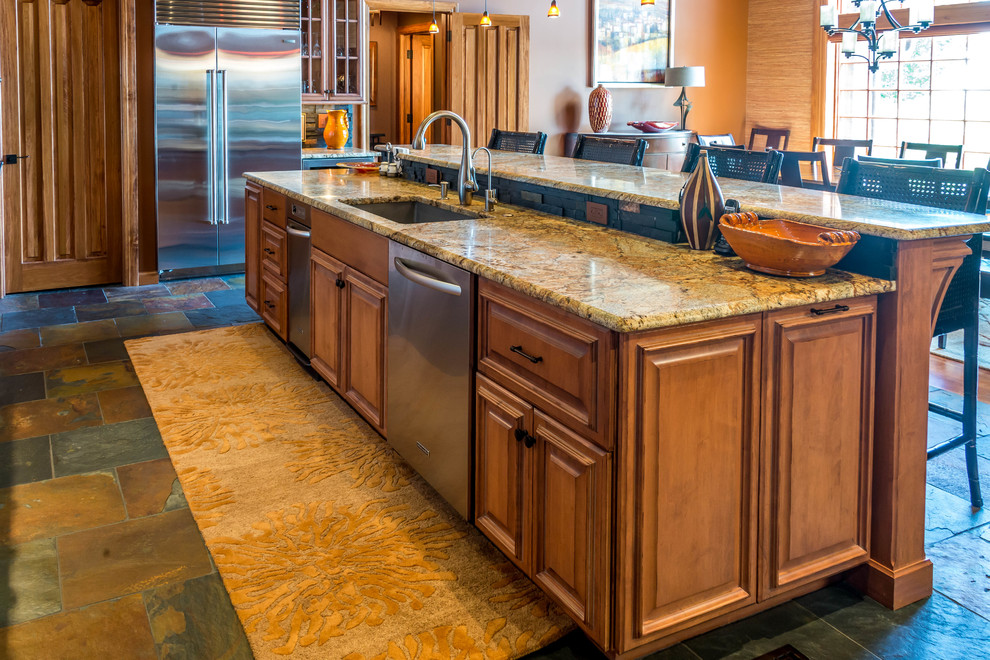Example of a small eclectic l-shaped slate floor open concept kitchen design with an undermount sink, raised-panel cabinets, light wood cabinets, granite countertops, black backsplash, stone tile backsplash, stainless steel appliances and an island
