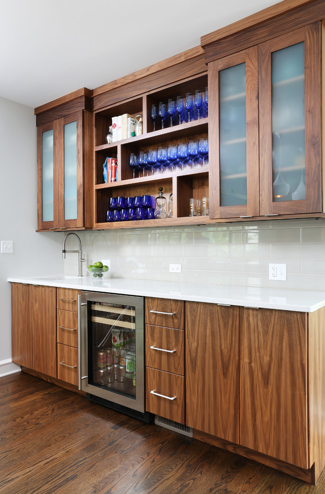 Photo of a large midcentury l-shaped eat-in kitchen in Chicago with a single-bowl sink, flat-panel cabinets, brown cabinets, stainless steel appliances, medium hardwood floors, with island, quartz benchtops, white splashback and ceramic splashback.