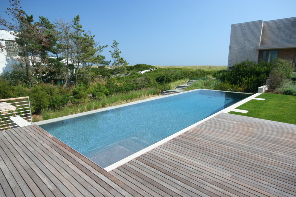 Photo of a beach style backyard rectangular infinity pool in New York with decking.