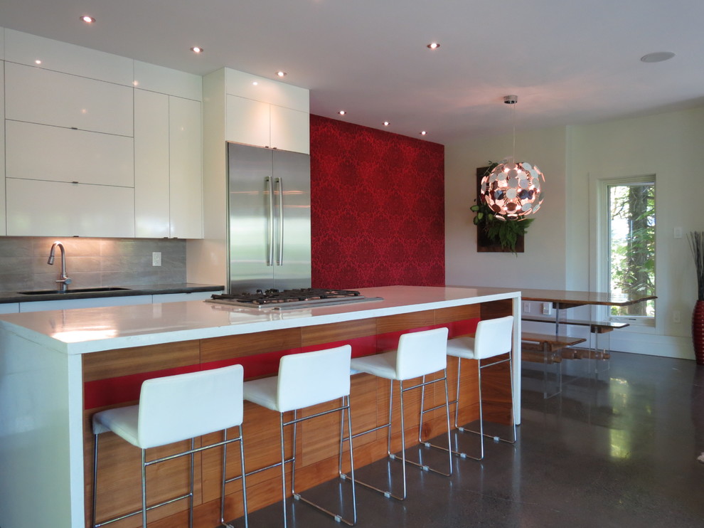 Photo of a large modern single-wall eat-in kitchen in Other with flat-panel cabinets, white cabinets, solid surface benchtops, grey splashback, cement tile splashback, stainless steel appliances, slate floors and with island.