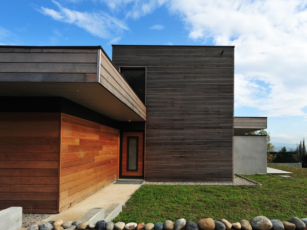 Mid-sized contemporary two-storey brown exterior in Other with wood siding and a flat roof.
