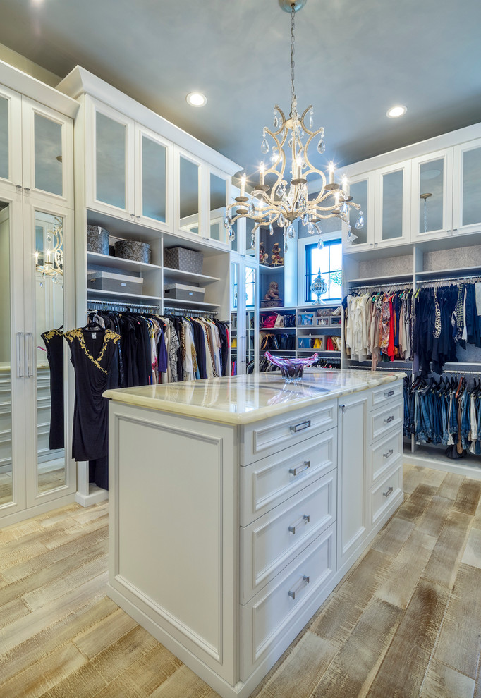 Design ideas for a large transitional gender-neutral walk-in wardrobe in Los Angeles with white cabinets, light hardwood floors and recessed-panel cabinets.