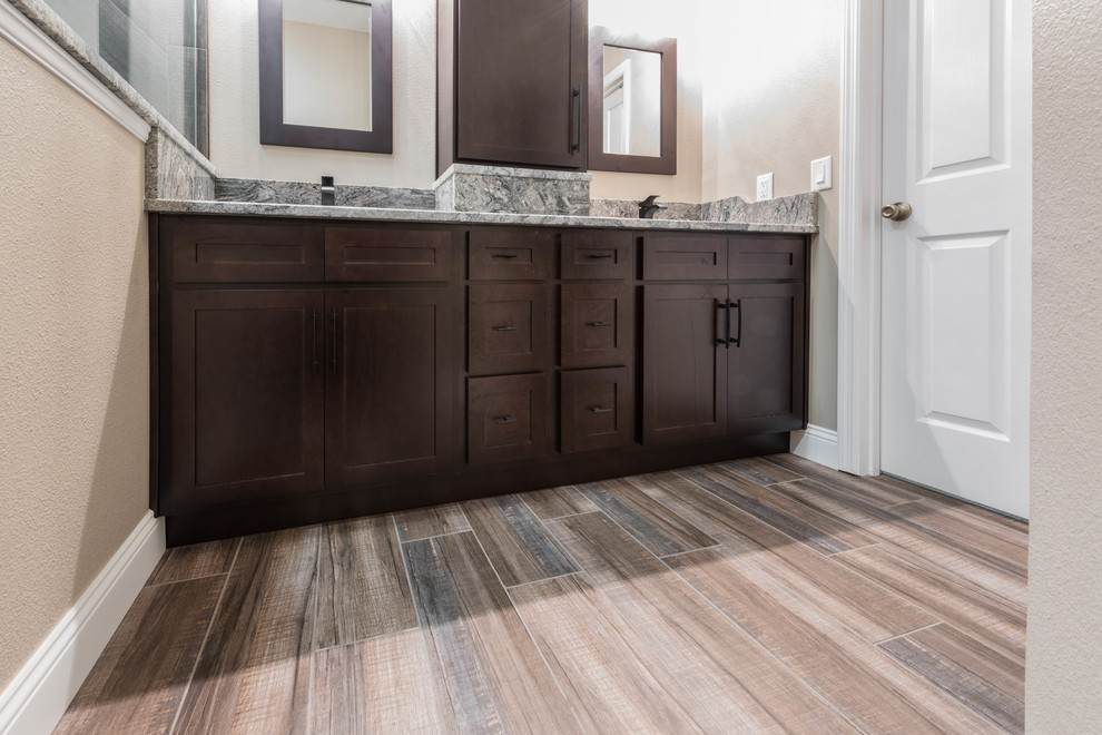 Design ideas for a mid-sized country master bathroom in Orlando with shaker cabinets, dark wood cabinets, an alcove shower, beige walls, porcelain floors, an undermount sink, granite benchtops, brown floor, an open shower and multi-coloured benchtops.