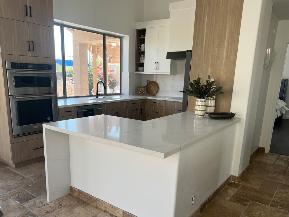 Example of a small transitional u-shaped travertine floor, beige floor and vaulted ceiling eat-in kitchen design in Phoenix with a drop-in sink, flat-panel cabinets, medium tone wood cabinets, quartz countertops, white backsplash, quartz backsplash, stainless steel appliances, an island and white countertops