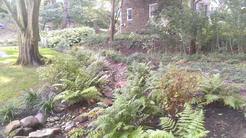 Photo of a mid-sized country backyard shaded garden in Philadelphia with a water feature and concrete pavers.