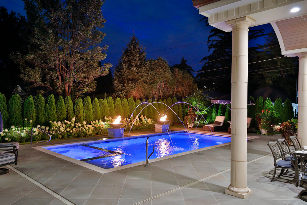 Photo of a mid-sized traditional backyard rectangular lap pool in Chicago with with privacy feature and natural stone pavers.