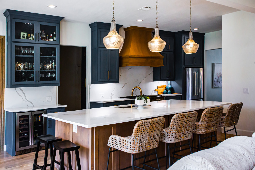 Inspiration for a mid-sized transitional single-wall open plan kitchen in Dallas with an undermount sink, shaker cabinets, quartz benchtops, stainless steel appliances, medium hardwood floors, with island, white benchtop, blue cabinets, white splashback and engineered quartz splashback.