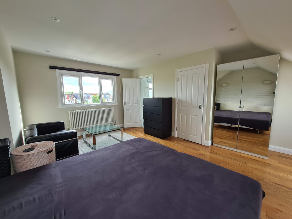 Geräumiges Modernes Schlafzimmer ohne Kamin mit beiger Wandfarbe, dunklem Holzboden, Kaminumrandung aus Backstein, braunem Boden, eingelassener Decke und Ziegelwänden in London