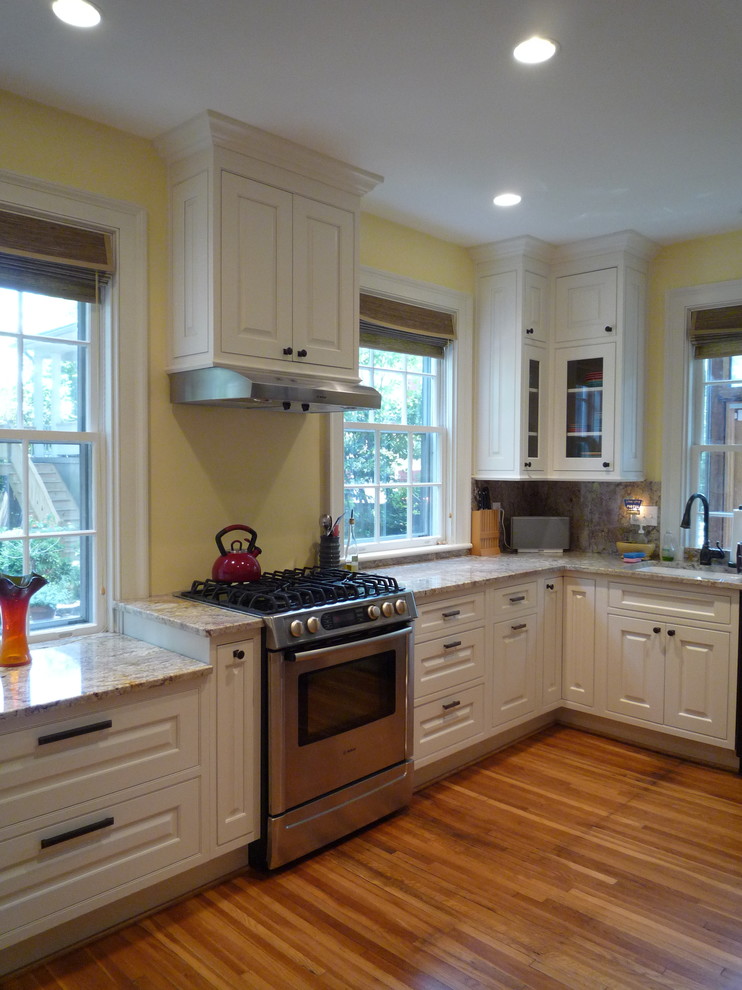 Inspiration for a mid-sized transitional l-shaped medium tone wood floor and brown floor enclosed kitchen remodel with an undermount sink, raised-panel cabinets, white cabinets, granite countertops, multicolored backsplash, stone slab backsplash, stainless steel appliances and no island