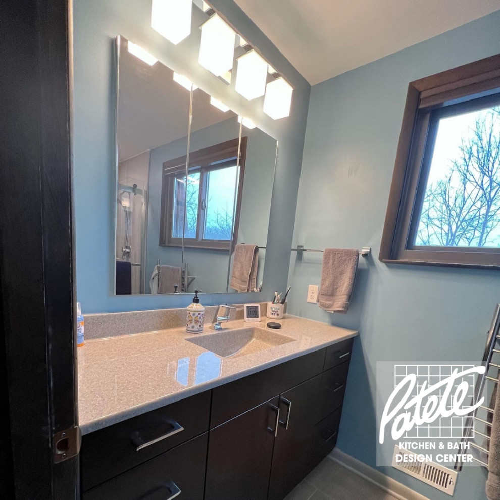 This is an example of a beach style bathroom in Other with flat-panel cabinets, brown cabinets, gray tile, limestone, blue walls, quartzite benchtops, a sliding shower screen, beige benchtops, a single vanity and a built-in vanity.