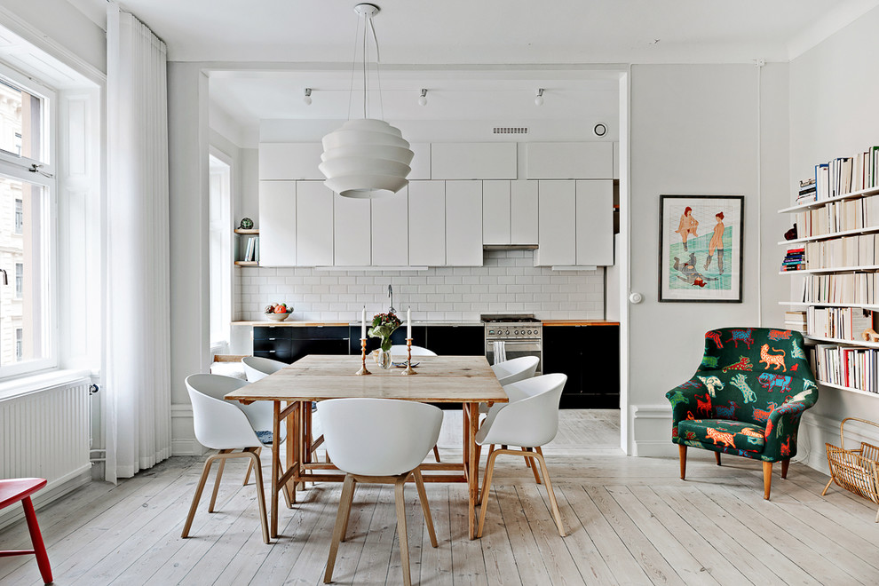 Mid-sized scandinavian kitchen/dining combo in Stockholm with white walls and painted wood floors.
