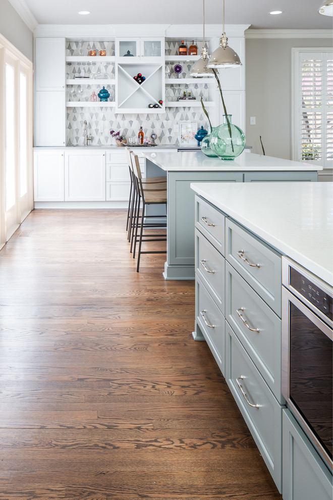 Example of a huge transitional galley medium tone wood floor open concept kitchen design in Raleigh with a farmhouse sink, flat-panel cabinets, white cabinets, quartz countertops, gray backsplash, ceramic backsplash, stainless steel appliances and two islands