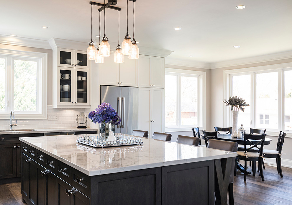 Inspiration for a large transitional l-shaped dark wood floor open concept kitchen remodel in Toronto with an undermount sink, recessed-panel cabinets, white cabinets, quartzite countertops, white backsplash, subway tile backsplash, stainless steel appliances and an island