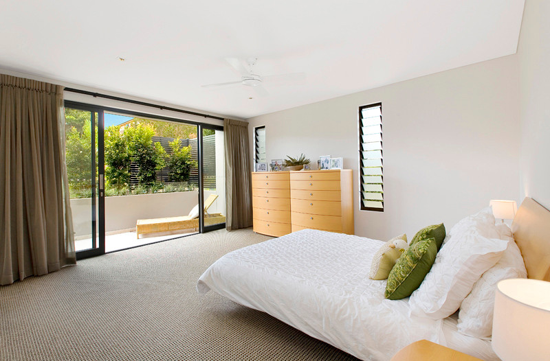 This is an example of a large contemporary master bedroom in Sydney with white walls, carpet and no fireplace.