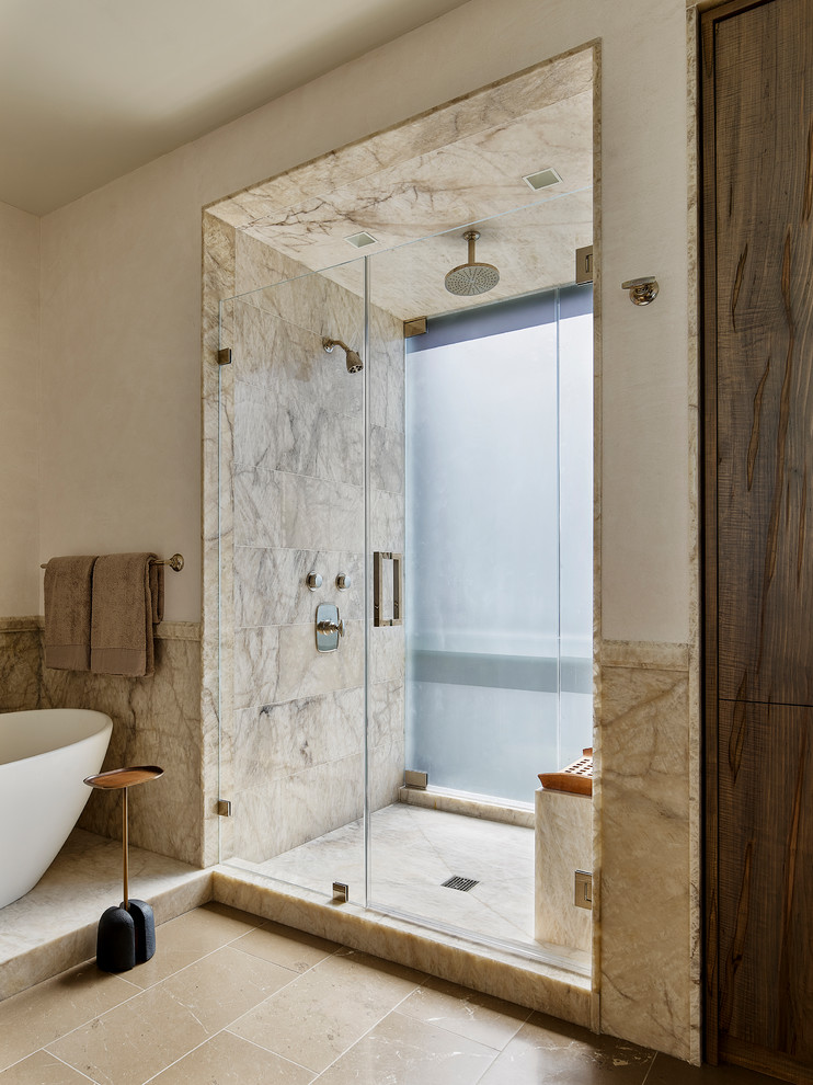 Design ideas for a large contemporary master bathroom in Philadelphia with flat-panel cabinets, medium wood cabinets, a freestanding tub, an alcove shower, beige tile, stone tile, white walls, limestone floors, limestone benchtops, beige floor, a hinged shower door and beige benchtops.