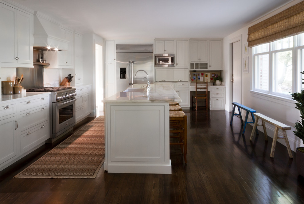 Large transitional u-shaped eat-in kitchen in Boston with stainless steel appliances, white cabinets, white splashback, dark hardwood floors and with island.