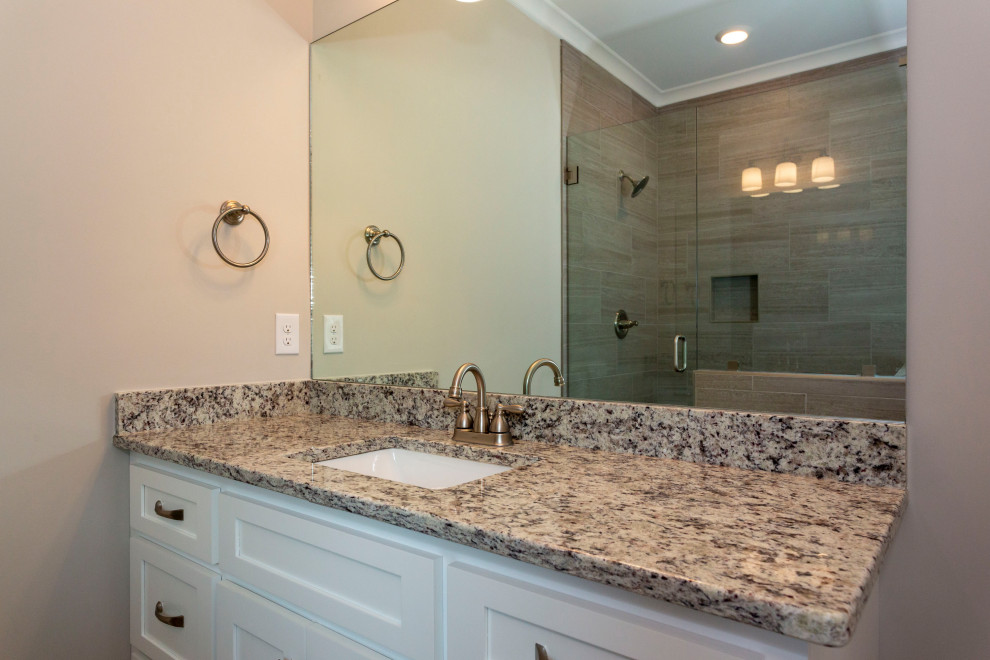 Inspiration for a mid-sized country master bathroom in Birmingham with shaker cabinets, white cabinets, a freestanding tub, gray tile, ceramic tile, grey walls, granite benchtops, grey floor, a hinged shower door, multi-coloured benchtops, a shower seat, a double vanity and a built-in vanity.