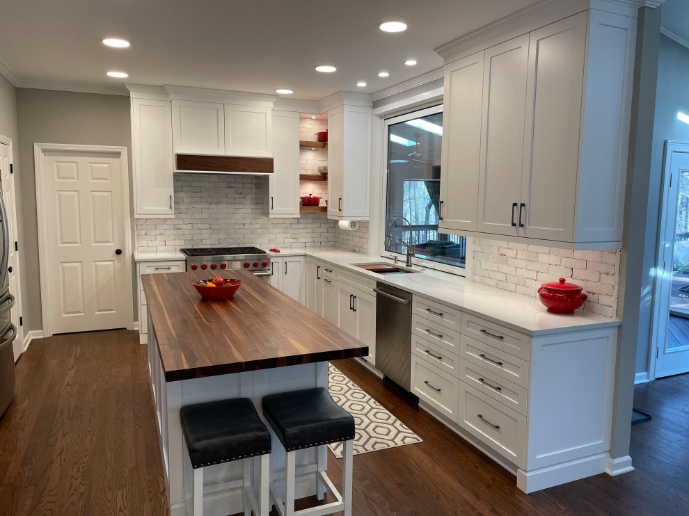 Kitchen - medium tone wood floor and brown floor kitchen idea in Atlanta with an undermount sink, recessed-panel cabinets, white cabinets, white backsplash, stainless steel appliances, an island and white countertops