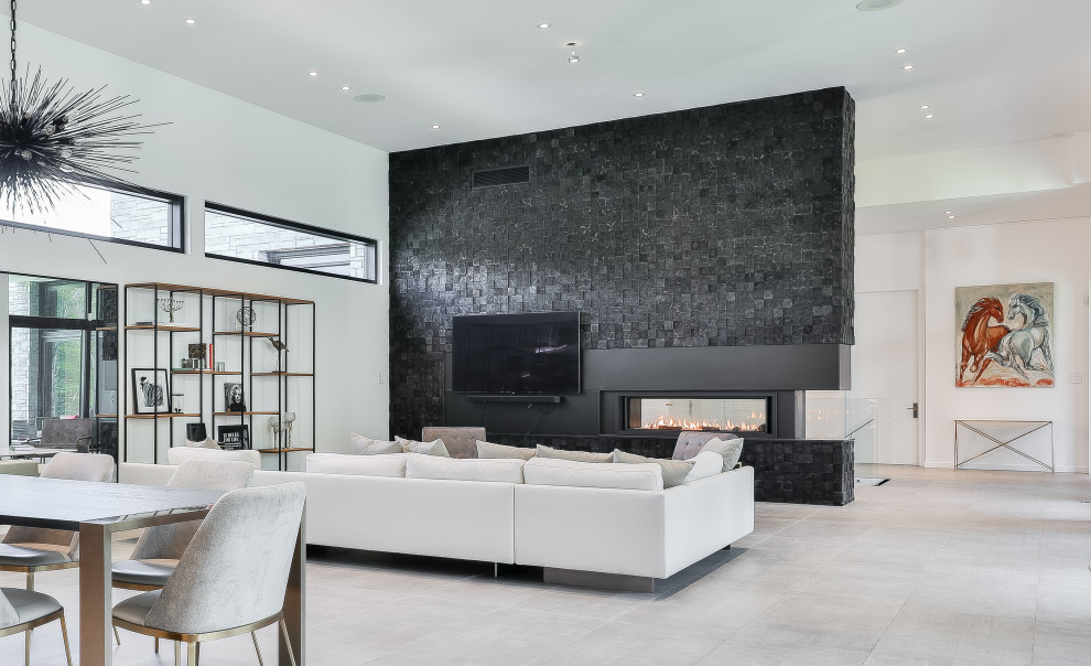 Großes, Offenes Modernes Wohnzimmer mit weißer Wandfarbe, Keramikboden, Tunnelkamin, Kaminumrandung aus Holz, TV-Wand, grauem Boden und Holzwänden in Montreal