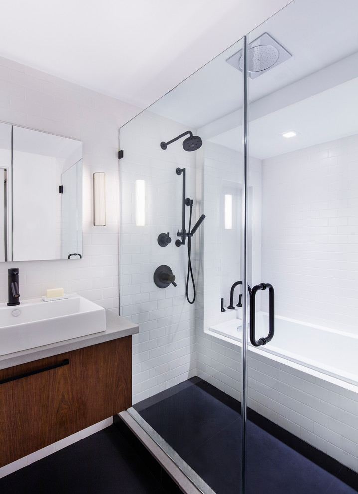 Photo of a mid-sized modern master bathroom in New York with a vessel sink, flat-panel cabinets, dark wood cabinets, concrete benchtops, a drop-in tub, an open shower, a wall-mount toilet, white tile, subway tile, white walls and porcelain floors.