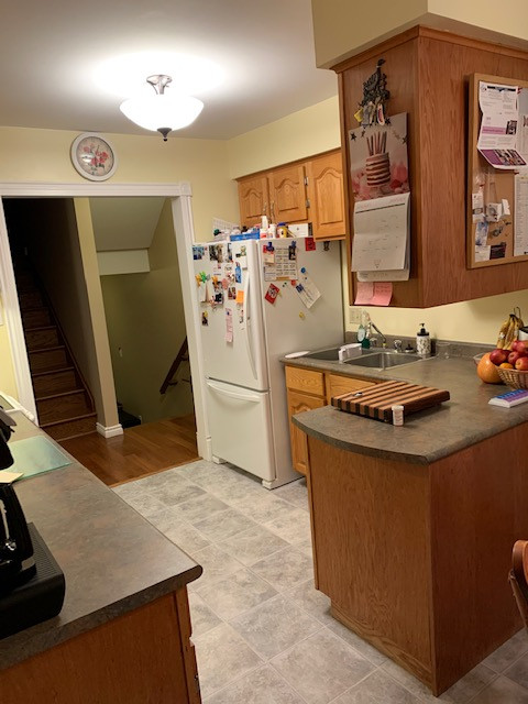 Mid-sized transitional galley enclosed kitchen photo with a drop-in sink, raised-panel cabinets, medium tone wood cabinets, laminate countertops, white appliances, a peninsula and gray countertops
