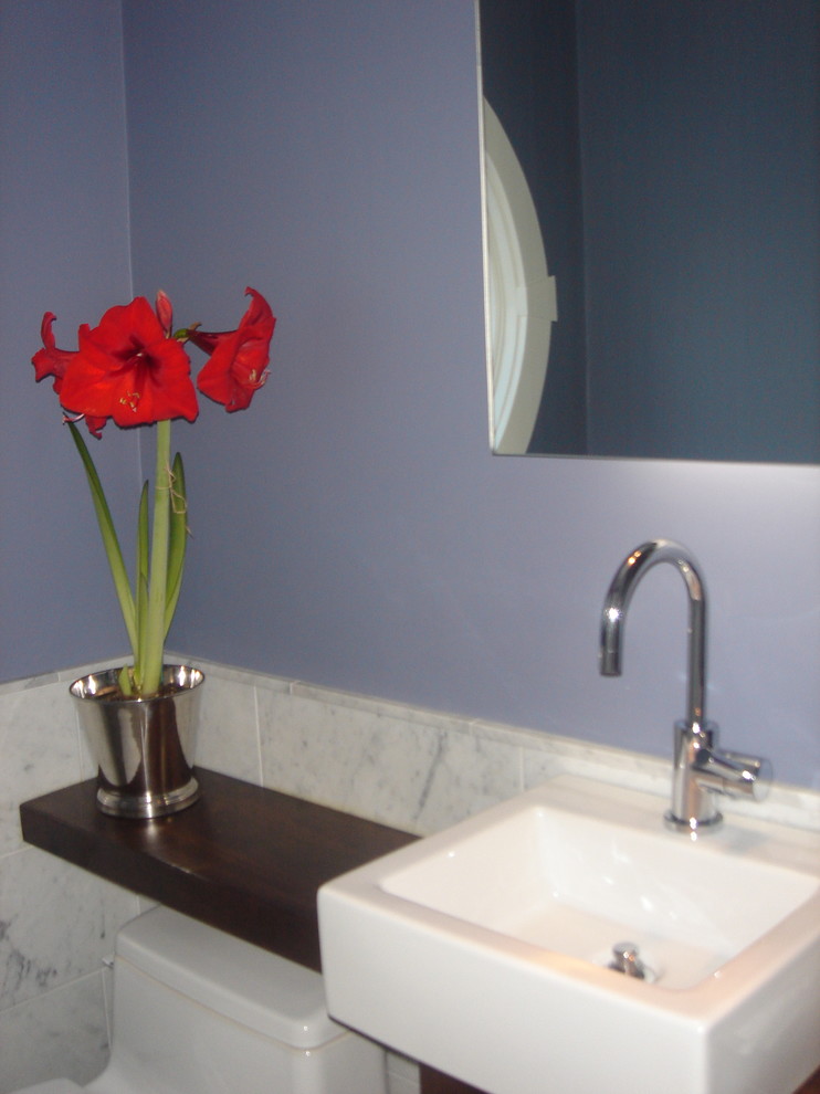 Mid-sized transitional powder room in Boston with flat-panel cabinets, wood benchtops, a one-piece toilet, gray tile, marble, blue walls and a drop-in sink.