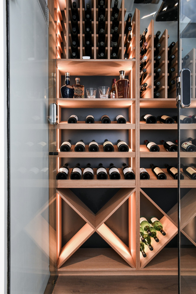 This is an example of a mid-sized modern wine cellar in Sydney with dark hardwood floors, storage racks and brown floor.