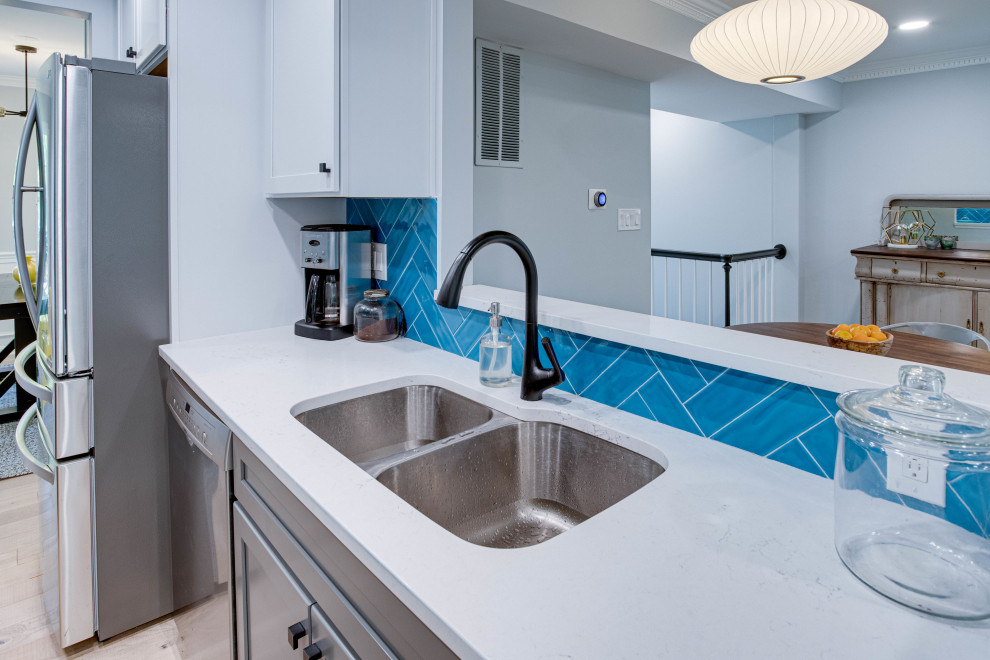 Example of a mid-sized transitional galley kitchen design in DC Metro with an undermount sink, shaker cabinets, quartz countertops, blue backsplash, stainless steel appliances and no island