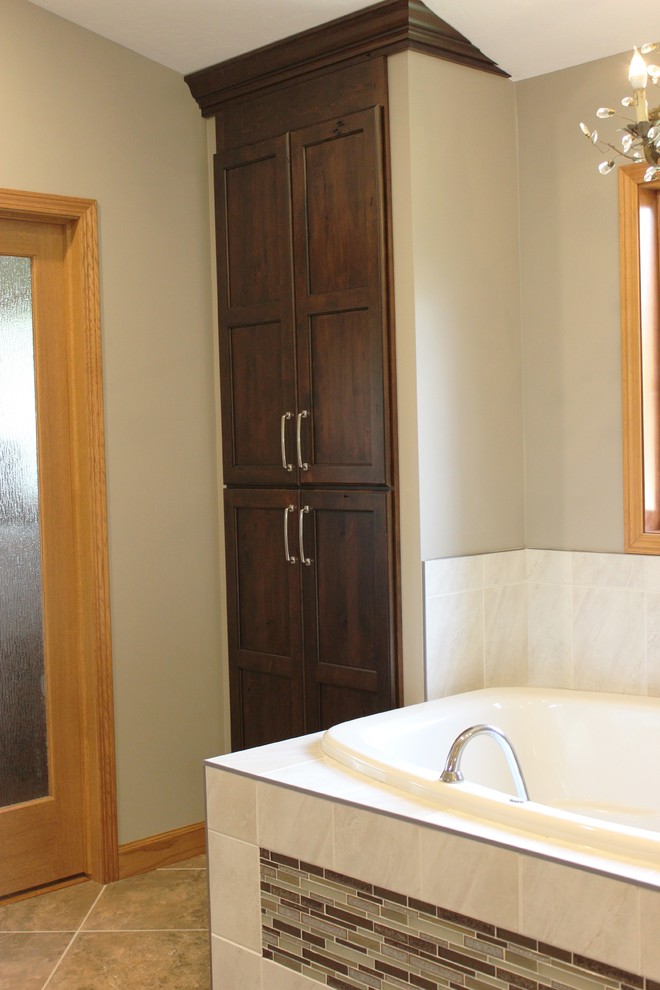 Photo of a large traditional ensuite bathroom in Chicago with raised-panel cabinets, dark wood cabinets, a built-in bath, a walk-in shower, beige tiles, ceramic tiles, beige walls, ceramic flooring, a vessel sink and engineered stone worktops.