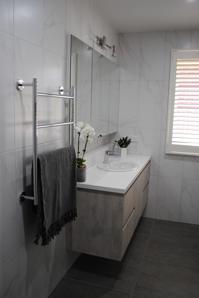 Photo of a mid-sized contemporary master bathroom in Other with furniture-like cabinets, grey cabinets, an open shower, a two-piece toilet, white tile, ceramic tile, white walls, porcelain floors, a drop-in sink, laminate benchtops, grey floor and an open shower.