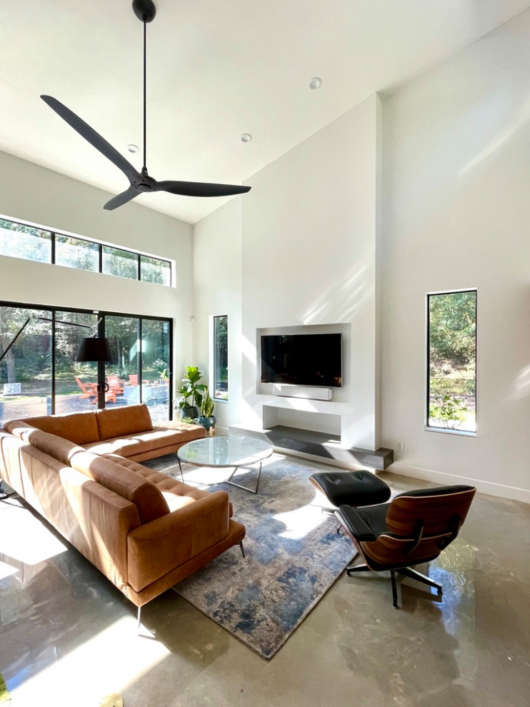 Mid-sized modern open concept living room in Houston with white walls, concrete floors, a wall-mounted tv and grey floor.