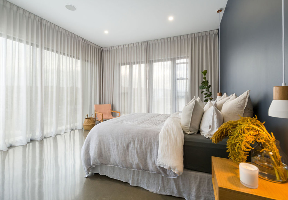 Large contemporary master bedroom in Other with blue walls, concrete floors and grey floor.