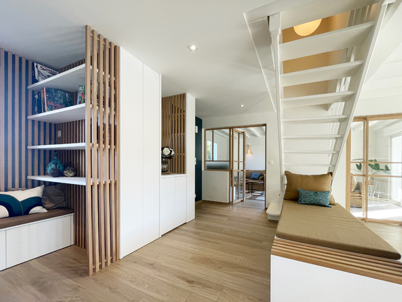 На фото: большая открытая гостиная комната в скандинавском стиле с синими стенами, деревянными стенами и с книжными шкафами и полками с