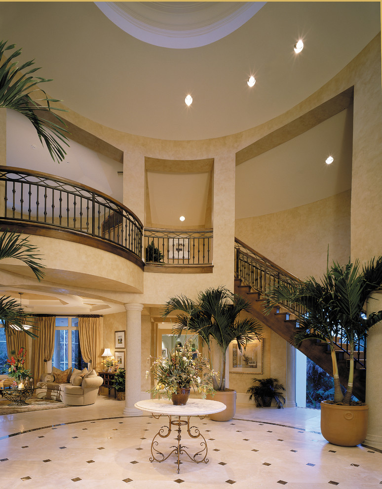 This is an example of an expansive mediterranean foyer in Miami with beige walls, travertine floors, a double front door and a dark wood front door.