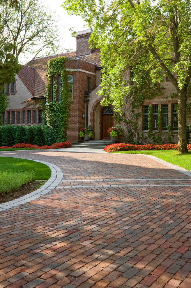This is an example of a large traditional front yard driveway in Minneapolis with brick pavers.