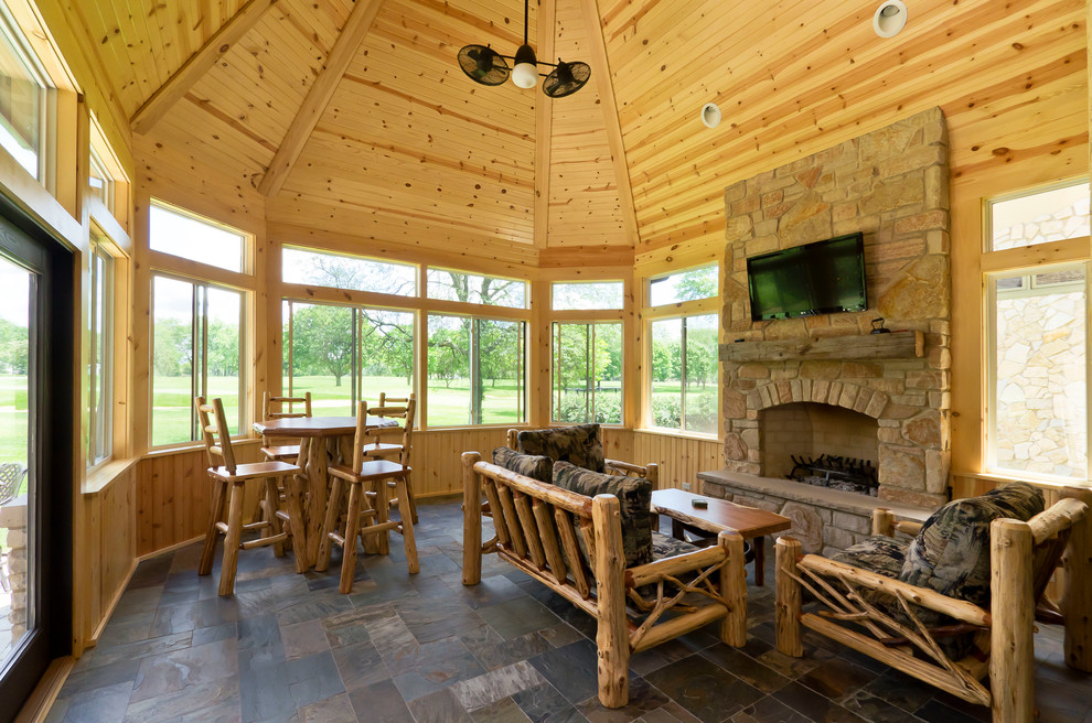 Photo of a mid-sized country sunroom in Chicago with slate floors, a standard fireplace and a stone fireplace surround.