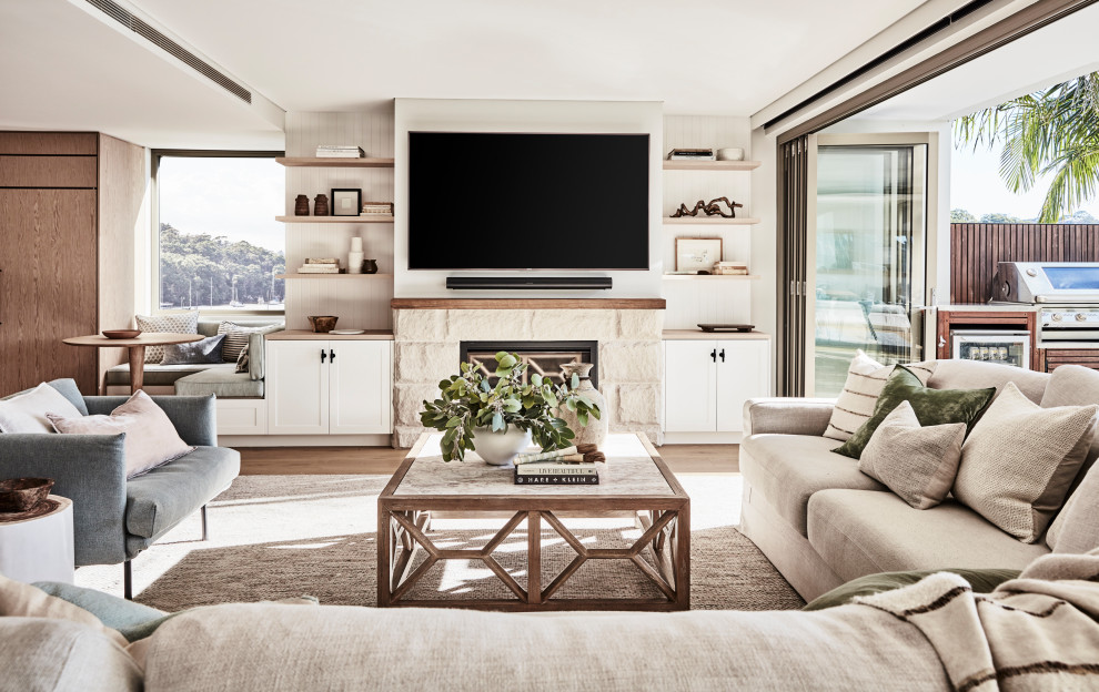 Großes, Offenes Maritimes Wohnzimmer mit weißer Wandfarbe, hellem Holzboden, Kaminumrandung aus Stein, TV-Wand und Wandpaneelen in Sydney