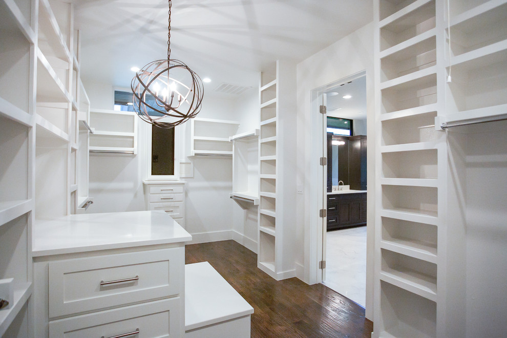 This is an example of a large transitional gender-neutral dressing room in Dallas with shaker cabinets, white cabinets, medium hardwood floors and brown floor.