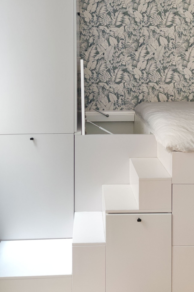 Immagine di una camera da letto moderna con pareti beige, parquet chiaro e carta da parati