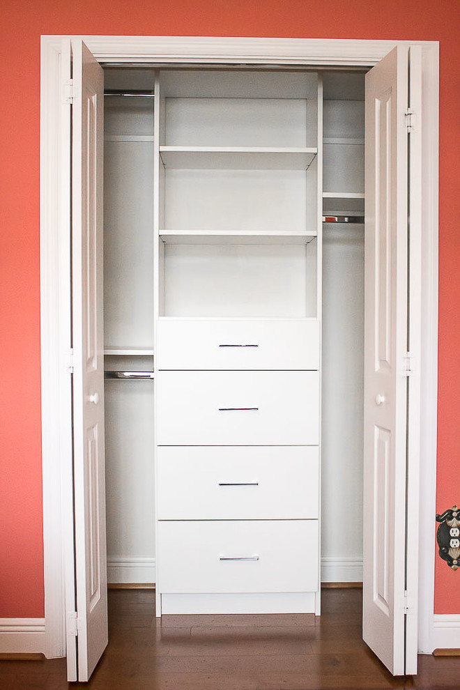 Photo of a small transitional gender-neutral built-in wardrobe in Orlando with flat-panel cabinets, white cabinets, medium hardwood floors and brown floor.