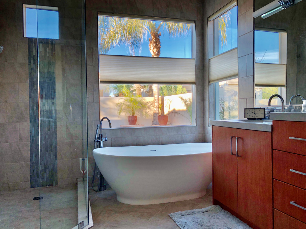 Inspiration for a mid-sized midcentury master bathroom in Phoenix with flat-panel cabinets, medium wood cabinets, a freestanding tub, a bidet, multi-coloured tile, white walls, an undermount sink, tile benchtops, multi-coloured floor, a hinged shower door, grey benchtops, an enclosed toilet, a double vanity, a freestanding vanity, porcelain floors and porcelain tile.