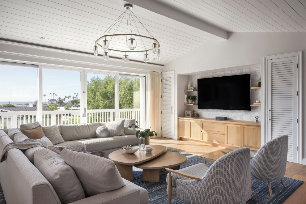 Example of a mid-sized beach style formal and open concept light wood floor and vaulted ceiling living room design in San Diego with a media wall