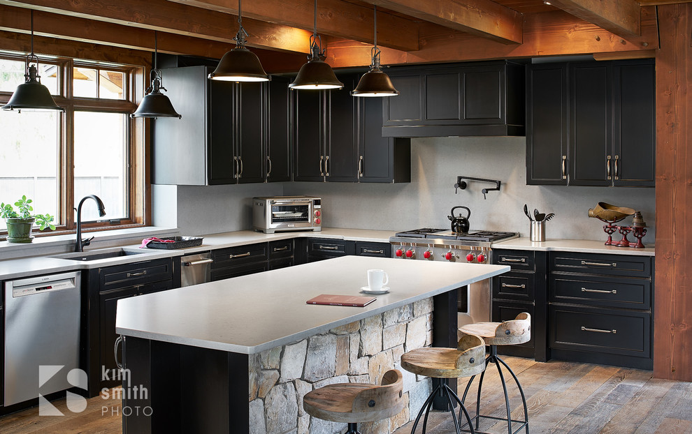 Imagen de cocina rústica con armarios con paneles lisos, electrodomésticos de acero inoxidable, suelo de madera en tonos medios y encimeras blancas